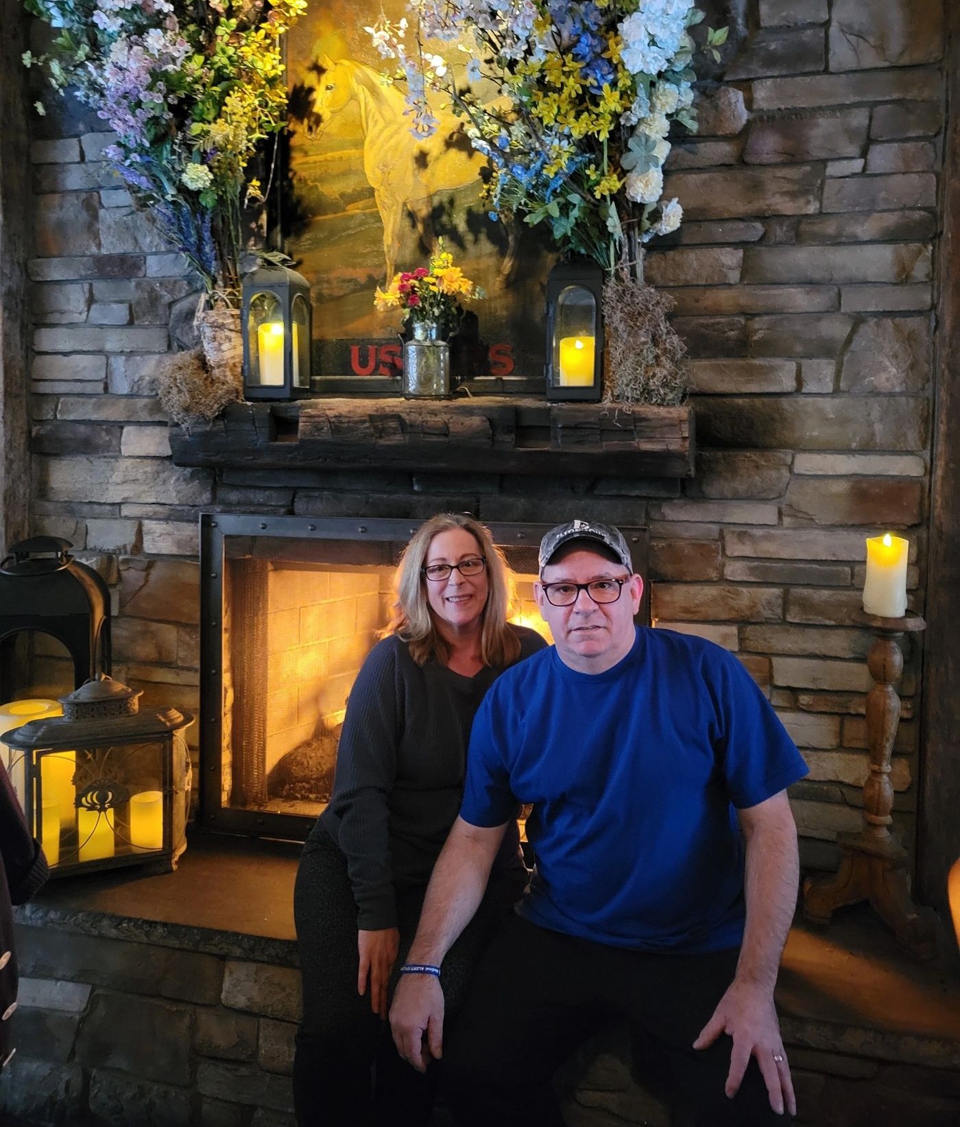 Dan and Gina Galpin, the husband-and-wife makers behind Regans Reflections, seated beside a stone fireplace